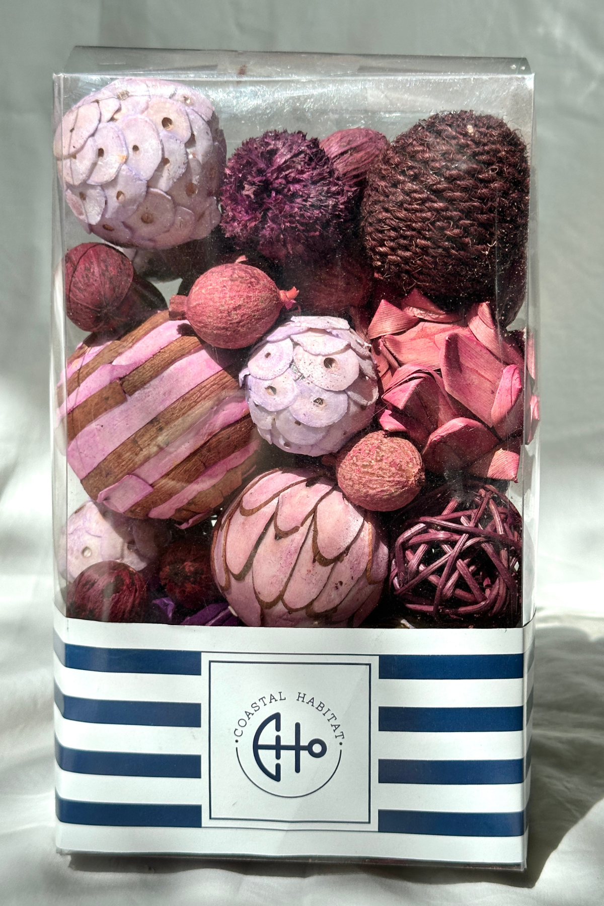 Box of chunky eco-friendly bowl fillers in shades of purple and pink, featuring dried flowers, woven natural spheres, and dried fruits arranged in a clear glass decorative bowl. Sustainable home decor accent.