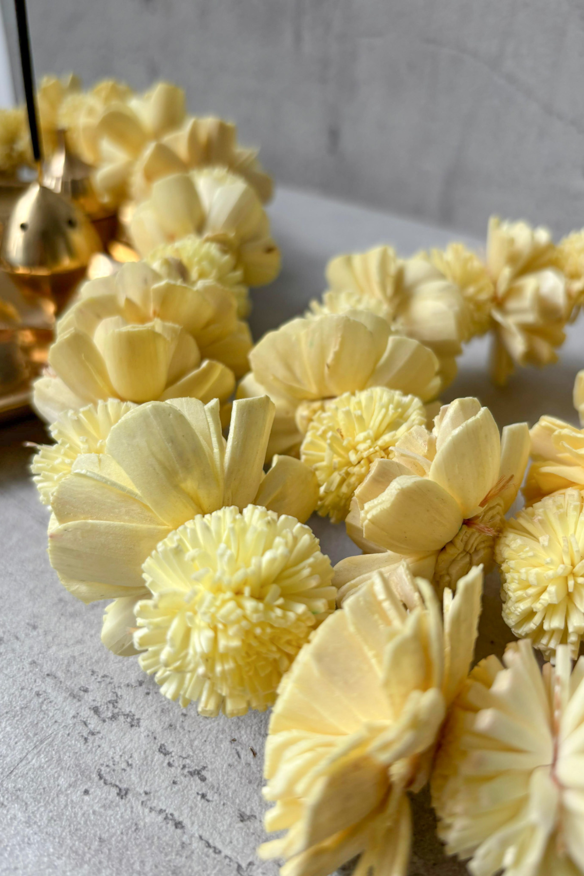 Close-up of a yellow shola flower garland (toran)  arranged along a string for decorative use.

